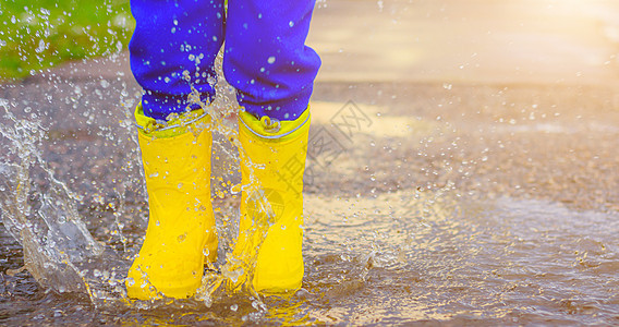 我的橡胶靴脚在水坑里蹦蹦跳跳 关于橡胶靴的文章 儿童夏季鞋 雨后的水坑 坏天气 一个孩子在水坑里跳 快乐的童年 一个穿着橡胶靴的背景图片