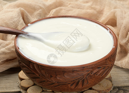 棕色陶瓷碗中的酸奶油 木制背景的木勺子 发酵牛奶有用产品奶制品白色酸奶营养食物餐巾盘子鞭打桌子背景