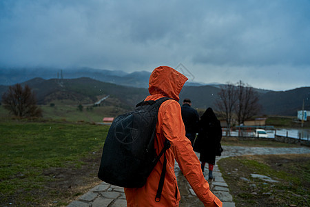 一个人穿着橙色雨衣 背着背包 走在山上的雨中行走远足者活动天气情感旅游游客娱乐旅行夹克下雨图片