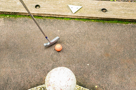 高尔夫球俱乐部和橙色球 在迷你高尔夫球场 用白标记箭图片