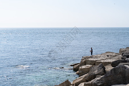 渔民站在海面岩石上 靠近英格兰Weymouth Dorset和Weymouth的波特兰比尔灯塔附近图片