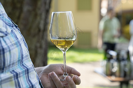 男性在户外饮酒时手握着一杯白葡萄酒奢华享受会议味道餐饮葡萄园用餐器皿酒厂质量图片
