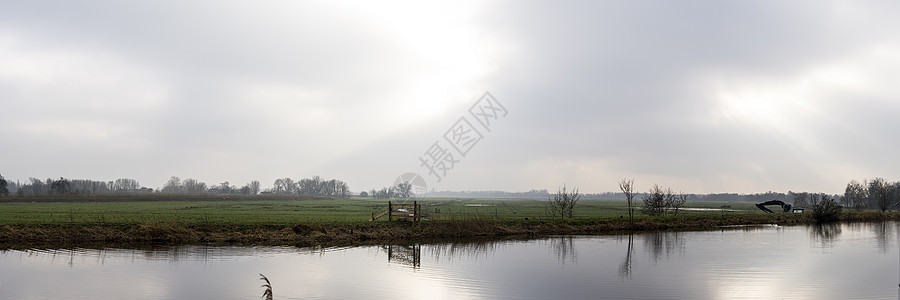 荷兰阿姆斯特丹附近农村地区的草地 河流或运河上空阴云密布 阳光普照图片