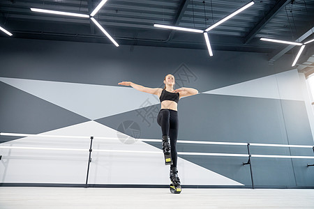 微笑的少女练习卡昂戈跳进室内健身房运动锻炼活动灵活性高科技鞋类袋鼠体操舞蹈图片
