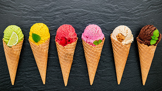 各种冰淇淋口味的锥体蓝莓 酸橙 开心果 杏仁 橙子 巧克力 香草和咖啡设置在深色石头背景上 夏季和甜蜜的菜单概念奶油糕点圣代水果图片