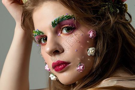 一个美丽的女孩与梦幻般的夏日妆容的画像 花丛中的春姑娘 长着眉毛和睫毛的豪华模特的脸 美容院概念图片