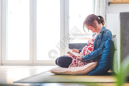 幸福的孕妇坐在地上 抱着她的肚子婴儿母亲孩子家庭父母地面孩子们微笑拥抱情绪图片