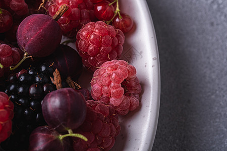 美味的新鲜成熟覆盆子 黑莓 醋栗和红醋栗浆果在盘子里 石混凝土背景上的健康食品水果 视角宏观图片
