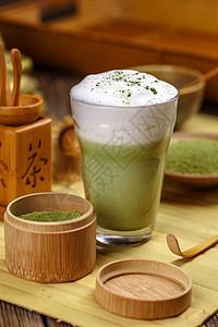 Matcha 绿色茶拿铁饮料玻璃粉末牛奶泡沫状美食桌子勺子杯子木头图片