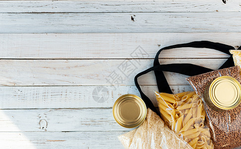 布袋零浪费与食品供应检疫食品危机隔离在一个木制的白色背景 大米 面食 罐头食品 玉米塑料 卫生纸 送餐 捐赠食物棉布袋志愿机构杂图片
