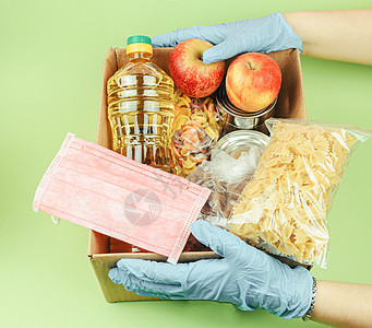 志愿者戴着防护手套 捐赠绿色背景的食品盒 送餐和病毒防护 捐赠和怜悯的概念社区包装饼干商品纸板瓶子宽慰麦片食品盒子图片