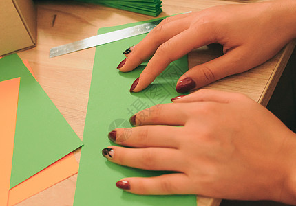 在前景中 一个女孩在木桌上准备折纸扇 彩色纸片和剪刀 一个风扇的几个空白 用于设计 广告或文本的模板图片