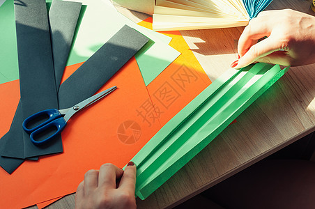 在前景中 女性的手正在为折纸扇 彩色纸片和木桌上的剪刀准备空白 一个风扇的几个空白 用于设计 广告或文本的模板工艺自由时间艺术联图片