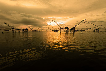 日出时天空的金光和泰国本土捕鱼工具 泰国图片