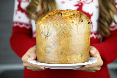 Panettone 是由一位身份不明的散焦女孩端到餐桌上的 身份不明的女人拿着 Panettone 传统意大利蛋糕过圣诞节 配上图片