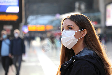 在机场戴外科口罩的女旅客特写 忧心忡忡的年轻女子正在查看出发到达时间表 等待她的航班信息图片