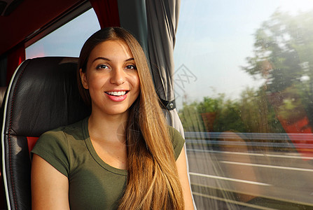 在公共汽车上微笑的美丽旅行者 女人看着相机图片