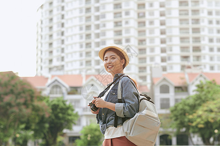 年轻美丽的亚洲背包旅行女郎 使用数码紧凑相机和微笑 看着复制空间建筑学摄影假期游客照片城市摄影师旅行旅游街道图片