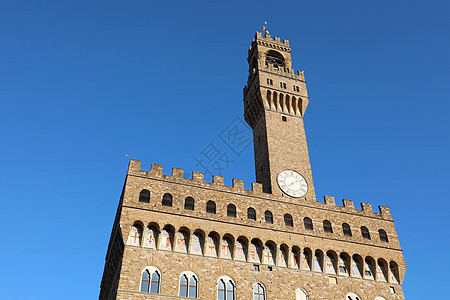 意大利佛罗伦萨广场上的市政厅宫殿 与钟楼的著名历史建筑与在蓝天背景的时钟图片