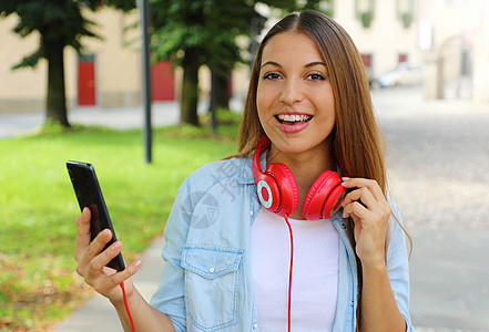 快乐女孩拥有智能手机 可以选择音乐 用她的新移动应用程序户外 看相机图片