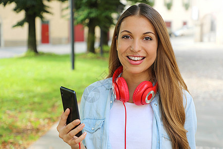 年轻女性拥有智能手机 可以选择音乐 用她新的移动应用程序户外 看镜头图片