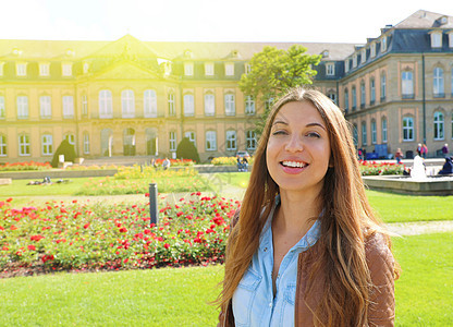 在德国斯图加特的新宫面前微笑着快乐的年轻女性情绪房子女士景观城堡旅行喷泉观光城市旅游图片