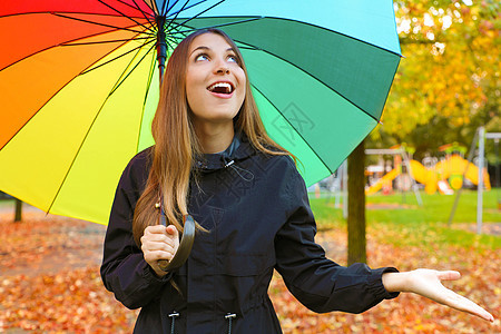 欢笑的年轻女人 带着色彩多彩的雨伞来寻找雨水图片