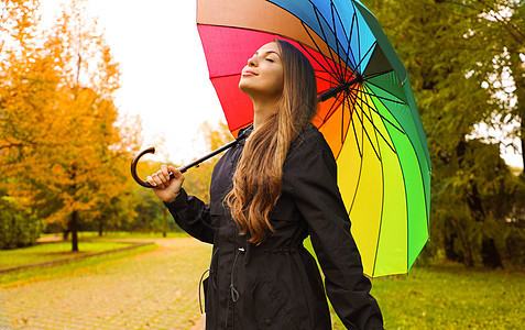 一位穿着雨衣的快乐女人在雨天 在城市公园呼吸时身着雨衣图片