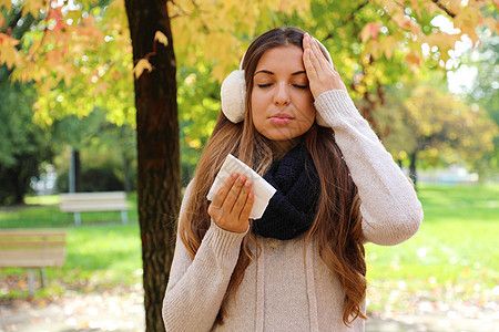 患有头痛寒热的年轻女性 拿着纸巾在户外图片