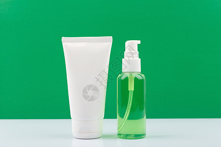 在绿色背景下白桌上的化妆品产品 面霜或润滑剂和皮肤泡沫或凝胶图片