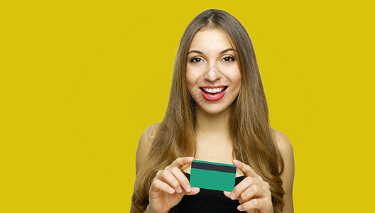 带着长头发的快乐年轻女孩的近距离肖像 她展示了因黄色背景而孤立的信用卡女性银行信用塑料支付折扣头发女士投资购物图片
