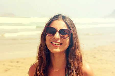 美丽的黑发女人的肖像在阳光明媚的白天带着太阳镜在海滩上微笑 以古老的过滤器为图像发型头发魅力女孩女性爆头女士眼镜拉丁潮人图片