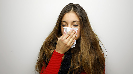 女孩在灰色背景上吹鼻涕 站立于灰色背景之下手帕发烧组织感染工作室女性流感鼻子冷冻卫生图片