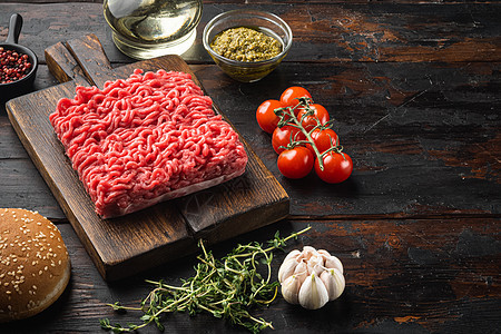 用胡椒 草药和香料混合鲜生肉 用于烹饪肉丸汉堡 木制切割板 旧的黑木桌背景以及文字复制空间图片