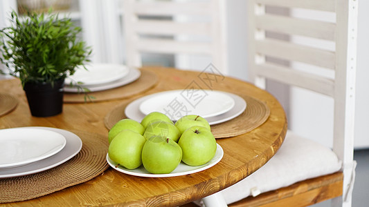 木制桌子上白盘子上的绿色苹果 白色扫描腹部水果陶瓷房间建筑学晴天枕头房子植物阁楼窗户图片