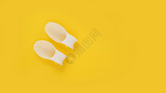 黄色背景上的白硅胶手指隔切器裁剪肌腱女性脚趾软垫玉米治疗水泡赤脚药品图片