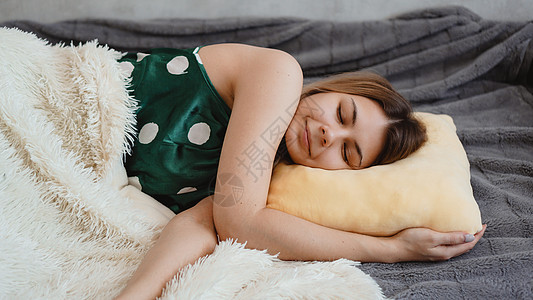 穿绿色睡衣的年轻美女 睡在黄色枕头上房间羽绒被说谎闲暇乐趣沙发女孩成人小憩女性图片
