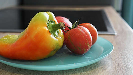 厨房灯光背景的蓝色盘子上的番茄和胡椒农业蔬菜面包板辣椒纤维饮食产品沙拉味道花园图片