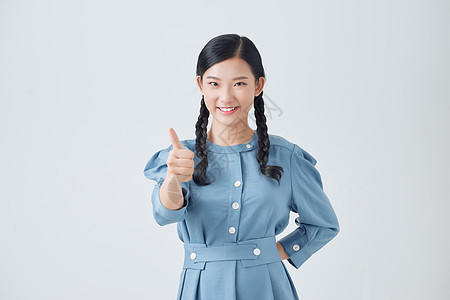 令人兴奋的年轻亚裔青少年举起拇指 与白种背景隔绝 积极评价的概念学生女士女孩微笑女性幸福喜悦成人快乐图片
