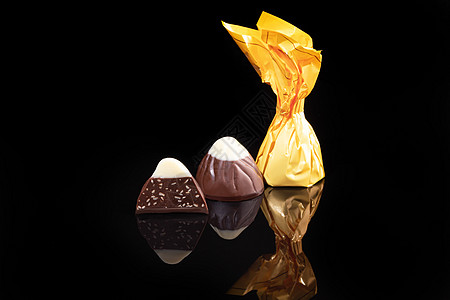 巧克力糖果在深色背景上 带反射 逐块和整块 充斥着坚果和水果薄荷食物酒吧牛奶李子大豆盒子棉花活力花生图片