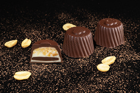 巧克力糖果在深色背景上 带反射 逐块和整块 充斥着坚果和水果活力棉花可可食物李子包装纸甜蜜甜点薄荷大豆图片