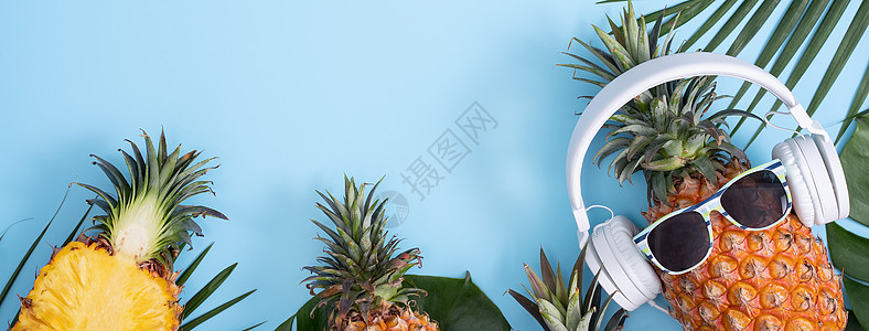 穿着白色耳机的有趣的菠萝 听音乐的概念 与热带棕榈叶隔绝在彩色背景上 高视线 平板设计平铺蓝色食物太阳镜乐趣高架叶子凤梨音乐潮人图片