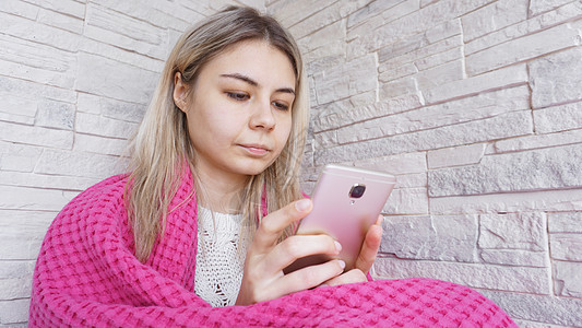 坐在窗台上的漂亮女孩 手拿着智能手机坐着成人女性播客衣服牛仔裤女孩房子格子衬衫技术图片