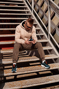 一名年轻人坐在城市的台阶上 城市风格 生活方式照片街道技术运动员青年帽子耳机短裤细胞金属成人图片