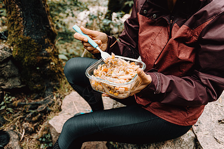 一个在森林里吃东西的女性远足者背包假期食物旅行瓶子木头远足野餐烹饪口渴图片