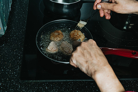 一个老西裔女人在厨房煎肉丸子台面食品杏仁女性蔬菜女士倾斜羊肉养分炊具图片