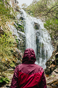 穿着紫色油皮的女人 站在巨大的瀑布前成人森林荒野旅行女性探索木头液体女士晴天图片