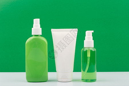 一套绿色和白色的化妆品瓶 在绿色背景图片