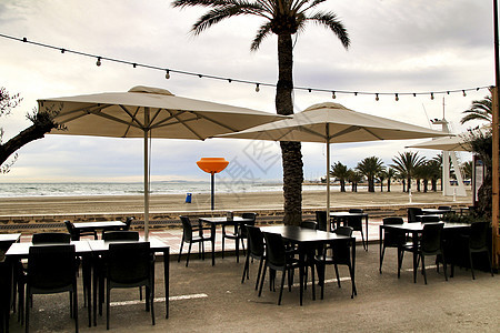 圣波拉海滩有露台的餐厅假期桌子海洋天空棕榈支撑食堂海浪奢华咖啡店图片