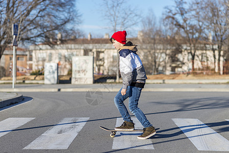 在沥青游乐场玩花样的滑板男孩 青少年滑板男孩夹克乐趣羊毛帽行动滑冰城市运动男性童年街道图片